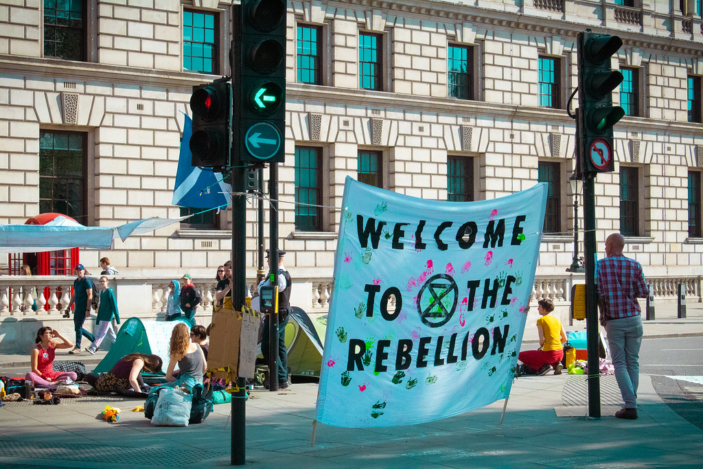Extinction Rebellion (XR) protesters carry a blue banner in London, reading 'welcome to the rebellion.'