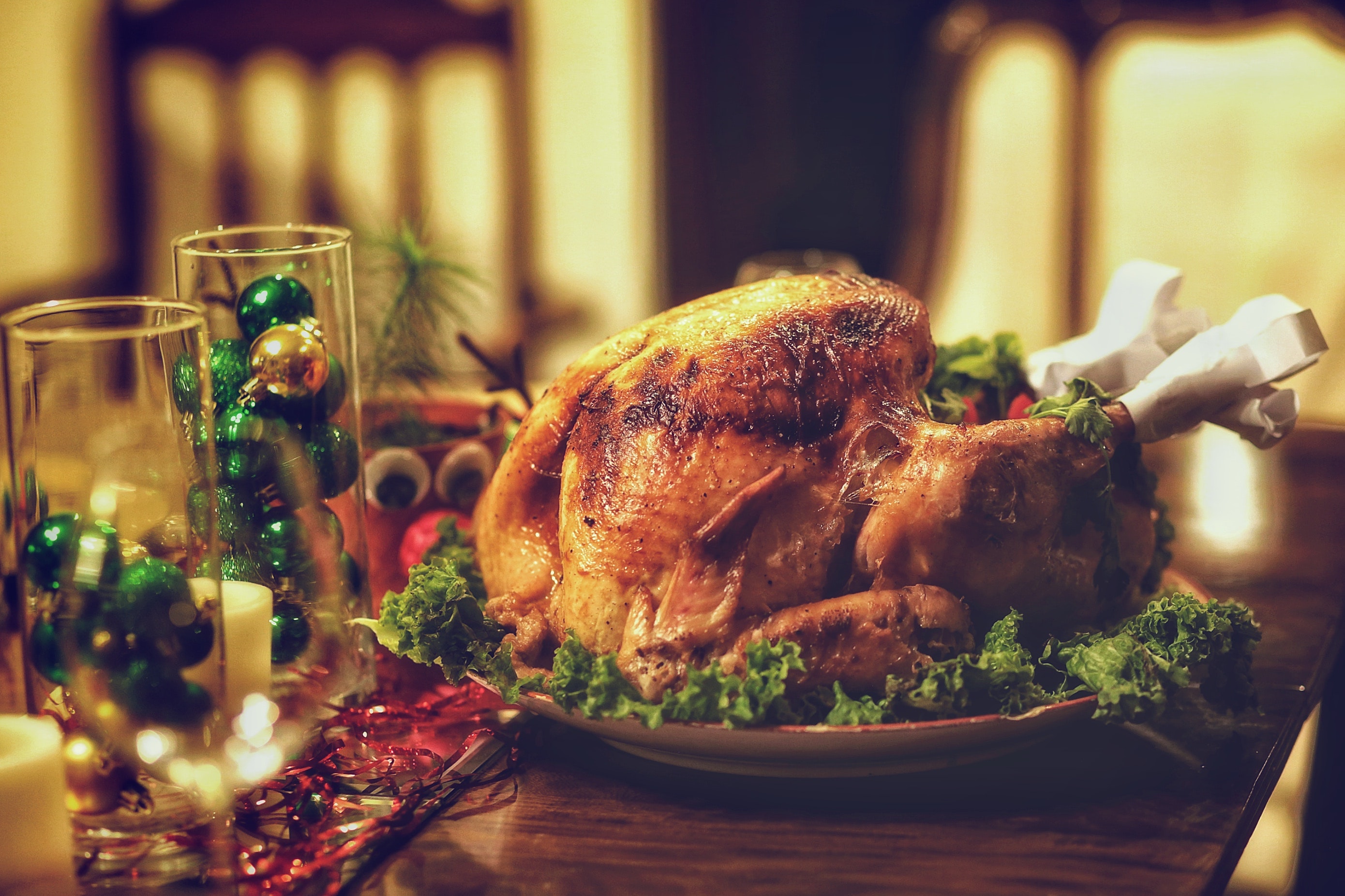 Roast chicken sat on a festively decorated table, complete with red and green decorations, candles and wine glasses