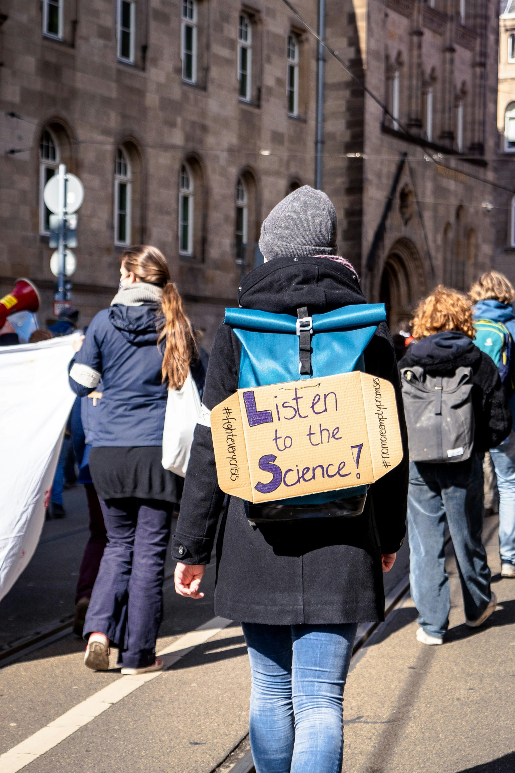 Protester holding a 'listen to the science!' banner